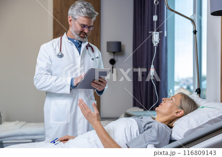 Doctor making a list of prescriptions to a patient in an intensive therapy department 116809143