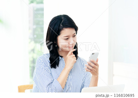 リビングでスマホを操作する女性 116810695