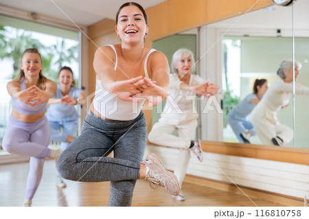 Ordinary active females exercising dance moves in modern dance studio 116810758