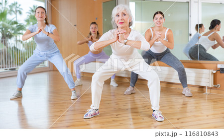Ordinary active females exercising dance moves in modern dance studio Ordinary active females exercising dance moves in modern dance studio 116810843