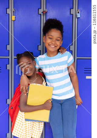 Portrait of happy african american schoolchildren standing next to locker in corridor at school Portrait of happy african american schoolchildren standing next to locker in corridor at school 116811555