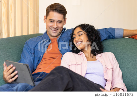 Relaxing on couch, young couple smiling and watching tablet together 116811672