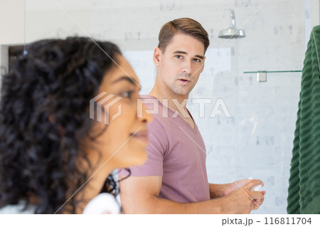 In bathroom, young couple getting ready, man looking at woman In bathroom, young couple getting ready, man looking at woman 116811704