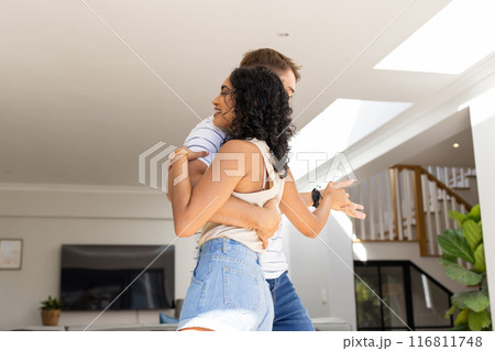 Young couple hugging and smiling in modern living room, enjoying time together Young couple hugging and smiling in modern living room, enjoying time together 116811748