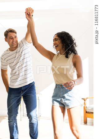 Dancing together, young couple enjoying time indoors, smiling and holding hands Dancing together, young couple enjoying time indoors, smiling and holding hands 116811773