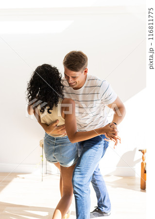 Young couple dancing together, enjoying fun and intimate moment indoors 116811775