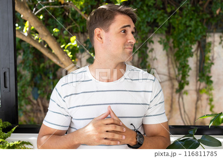 Young man in striped shirt standing and looking to side, outdoors Young man in striped shirt standing and looking to side, outdoors 116811785