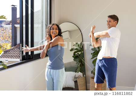Stretching together, young couple enjoying morning exercise routine at home 116811802