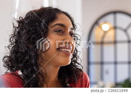 Smiling woman with curly hair looking away, enjoying moment indoors 116811849