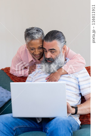 Senior couple using laptop together, smiling and enjoying time at home 116811911