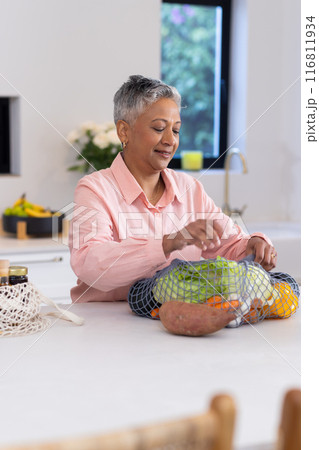 Unpacking groceries, senior woman organizing fresh vegetables in kitchen counter Unpacking groceries, senior woman organizing fresh vegetables in kitchen counter 116811934