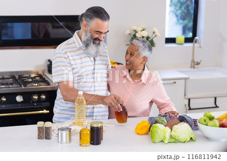 Senior couple preparing healthy meal with fresh vegetables in modern kitchen 116811942