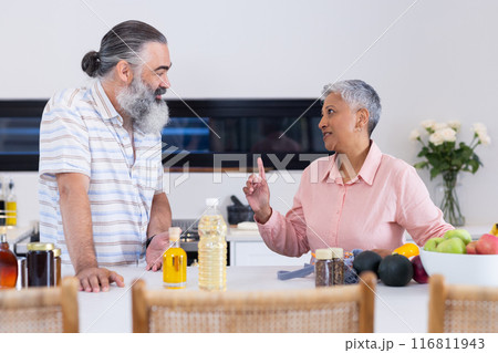 Senior couple discussing healthy cooking in modern kitchen with fresh produce 116811943