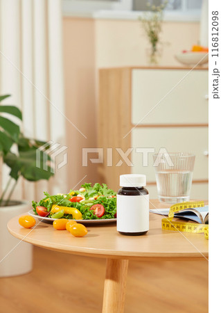 The unique template to design advertising pic of weight losing supplement, on the top of wooden table displaying some losing weight items and an unbranded drug bottle in center 116812098