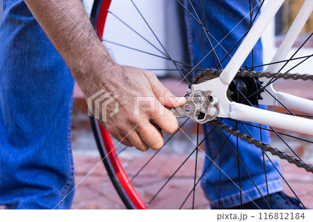 Repairing bicycle, man tightening bolt on bike wheel with wrench outdoors Repairing bicycle, man tightening bolt on bike wheel with wrench outdoors 116812184