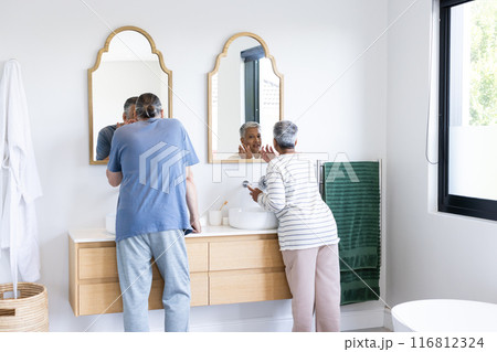 Brushing teeth, senior couple standing at bathroom sink, enjoying morning routine 116812324