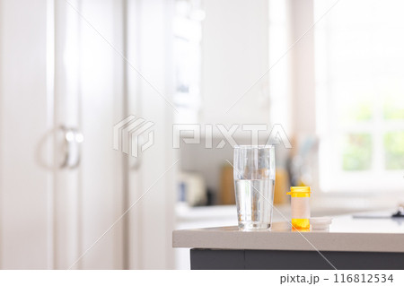 Close up of box of pills and glass of water on table in white kitchen 116812534