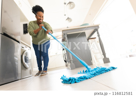 Happy senior african american woman cleaning floor with mop at home Happy senior african american woman cleaning floor with mop at home 116812581