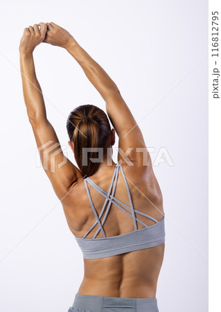 Young Caucasian female athlete stretches her arms on a white background, showcasing fitness 116812795