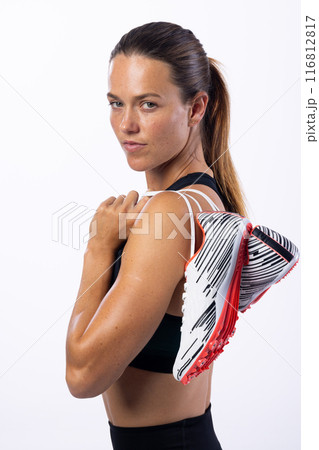 Young Caucasian female athlete holds running shoes over her shoulder on a white background 116812817