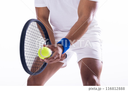 A young biracial man prepares to serve in a tennis match on a white background 116812888