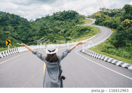 Asian tourist raised her hands while looking to beautiful steep curved road (look like number 3) on the high mountain in Nan province, Thailand. Asian tourist raised her hands while looking to beautiful steep curved road (look like number 3) on the high mountain in Nan province, Thailand. 116812963