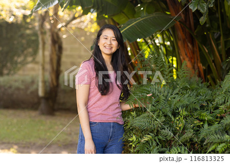 Smiling asian woman standing outdoors in garden, enjoying nature and greenery Smiling asian woman standing outdoors in garden, enjoying nature and greenery 116813325