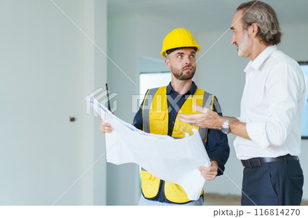 Portrait of caucasian male real estate customer talking - discussing with male building foreman - engineer about construction and interior works. Construction contractor talking with client. 116814270