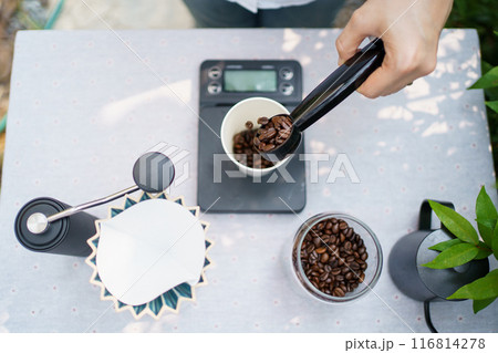 Happy Asian beautiful woman making a specialty coffee in morning at her backyard garden, woman brewing a coffee by dripping or pouring over a hot water. 116814278