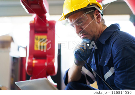 Senior professional electrical or industrial engineer inspecting and repairing a robotic system in the manufacturing factory close up. Robotic technician repairing - fixing a automated machine. 116814550