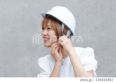 白いヘルメットをかぶった笑顔の女性。防災グッズと防災訓練のイメージ 116816883