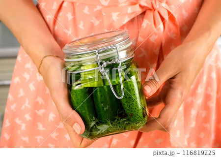 Woman holding glass jar with fresh pickles on kitchen at home, hands close-up. Woman holding glass jar with fresh pickles on kitchen at home, hands close-up. 116819225