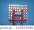 A red stadium light tower rises against a clear blue sky. 116819596