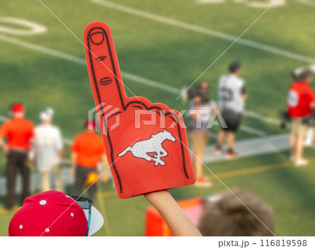 Calgary, Alberta, Canada. Jul 21, 2024. A fan holding a red foam finger with a Calgary Stampeders logo, cheering. 116819598
