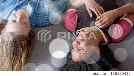 Image of light spots over two happy diverse teenage girls lying o bed talking Image of light spots over two happy diverse teenage girls lying o bed talking 116820425