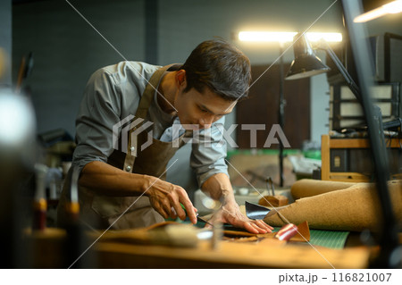 Handsome asian craftsman working meticulously in a workshop. Small business and handmade concept Handsome asian craftsman working meticulously in a workshop. Small business and handmade concept 116821007