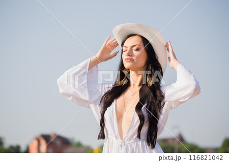 A woman in a white hat against a blue sky in summer A woman in a white hat against a blue sky in summer 116821042