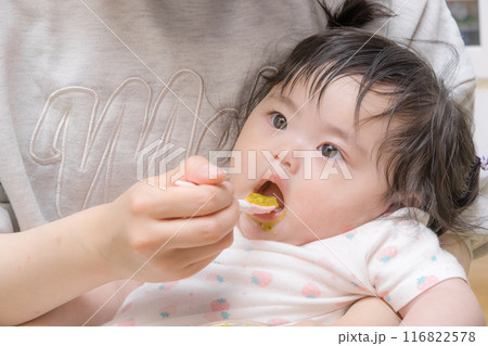 【離乳食を食べる髪を結んだ赤ちゃん】 116822578