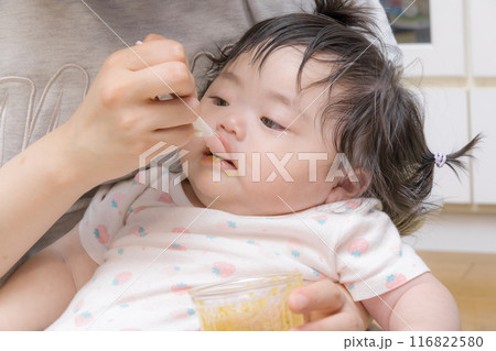 【離乳食を食べる髪を結んだ赤ちゃん】 116822580