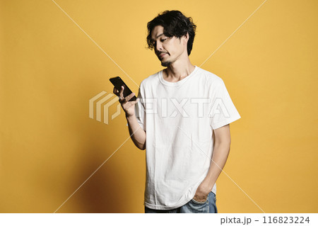 カラーバックでスマホを触る男性 116823224