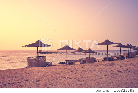 A tranquil beach with sun loungers and umbrellas at sunset, color toning applied, Egypt. 116823595