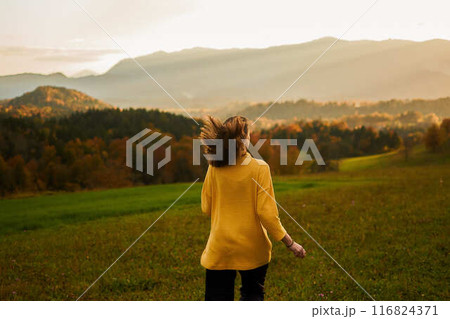 a young woman in mustard sweater in autumn mountains at sunset 116824371