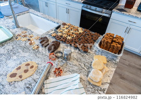 In a contemporary white kitchen, gingerbread cookie dough is skillfully rolled out, setting the stage for a delightful holiday treat. 116824982