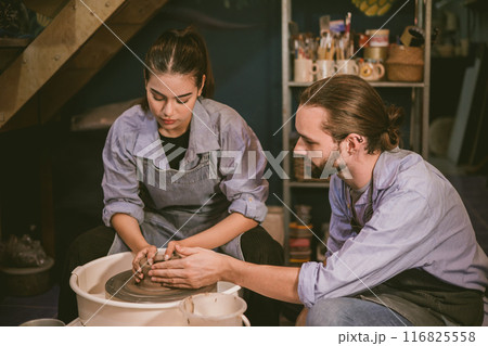 Man and woman hands working on pottery wheel and making a pot together lover couple. 116825558