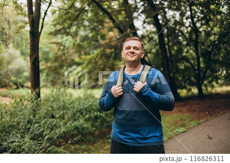 Happy man with backpack standing outside. One Caucasian male hiking in the woods. Travel, active lifestyle, people concept. Traveler enjoys eco-tourism, nature walks. Happy man with backpack standing outside. One Caucasian male hiking in the woods. Travel, active lifestyle, people concept. Traveler enjoys eco-tourism, nature walks. 116826311