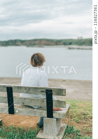 ベンチに座り海を眺める明るい茶髪の男性の後ろ姿 116827361