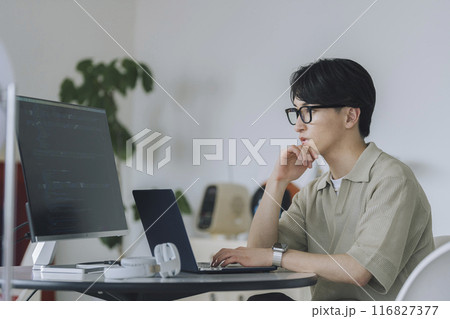 パソコンで作業をするメガネをかけた若い男性 116827377
