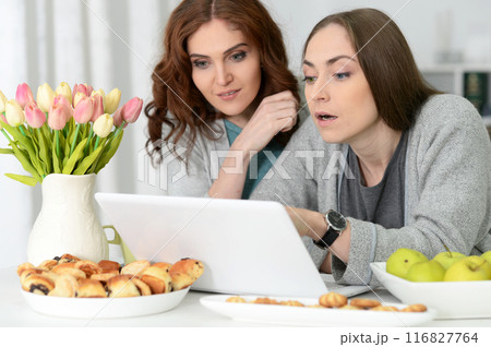 Two happy friends watching movie on laptop eating Two happy friends watching movie on laptop eating 116827764