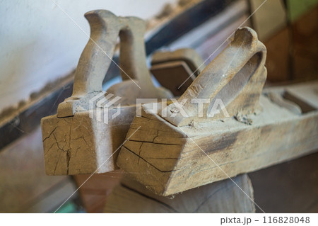 Two large old wooden jointers or planes stand idle without work, gathering dust exposed to weather, as result of which cracks have formed on body. Lack of maintenance of hand tools for carpentry Two large old wooden jointers or planes stand idle without work, gathering dust exposed to weather, as result of which cracks have formed on body. Lack of maintenance of hand tools for carpentry 116828048