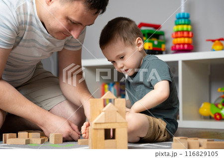 Little toddler boy 2,5 years playing wooden blocks with dad. Spending time with children. Educational activities for kids. Children's room. Indoors. Selective focus 116829105